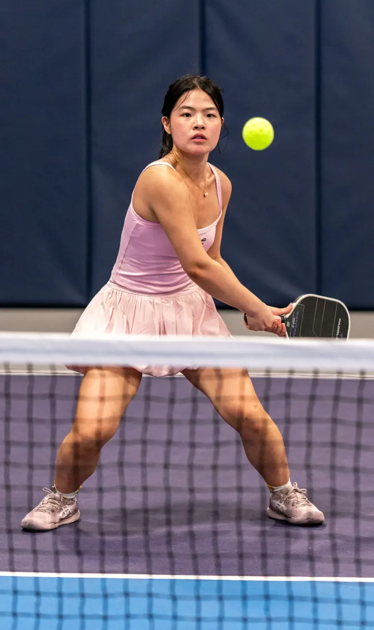 Player in athletic wear executing a backhand dink on an indoor pickleball court