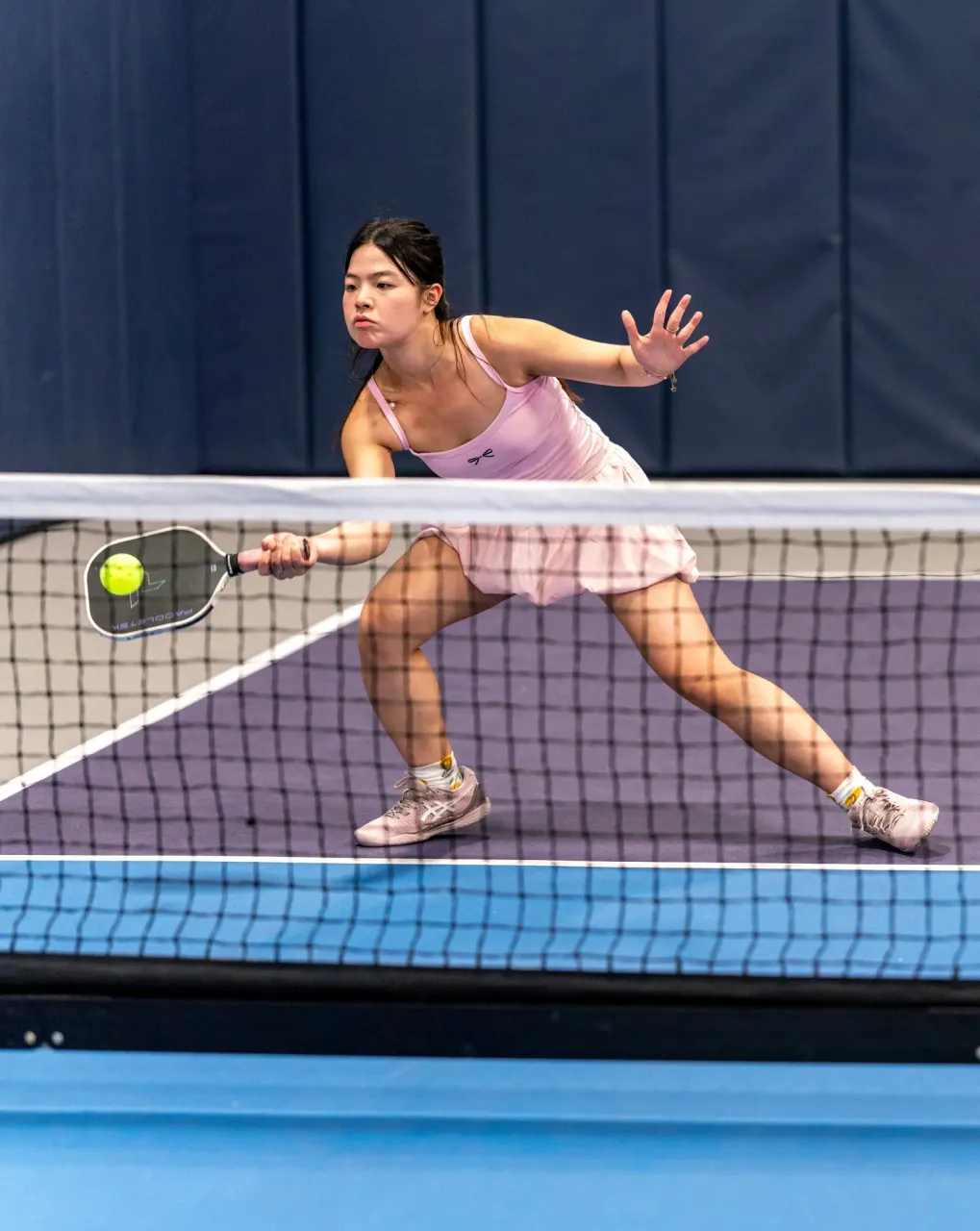 Player stretching for a volley during singles play at Pickleland