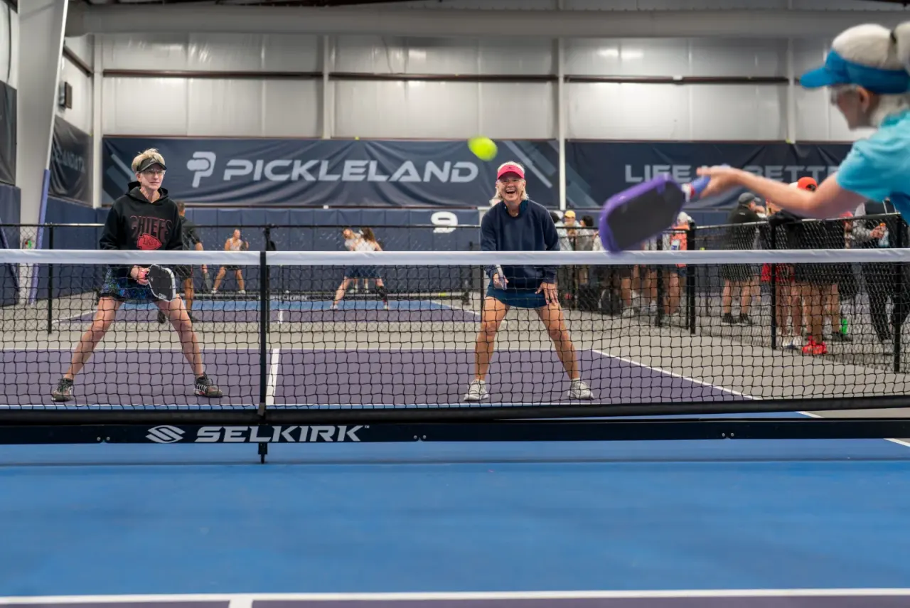 Doubles pickleball match in progress on an indoor court at Pickleland