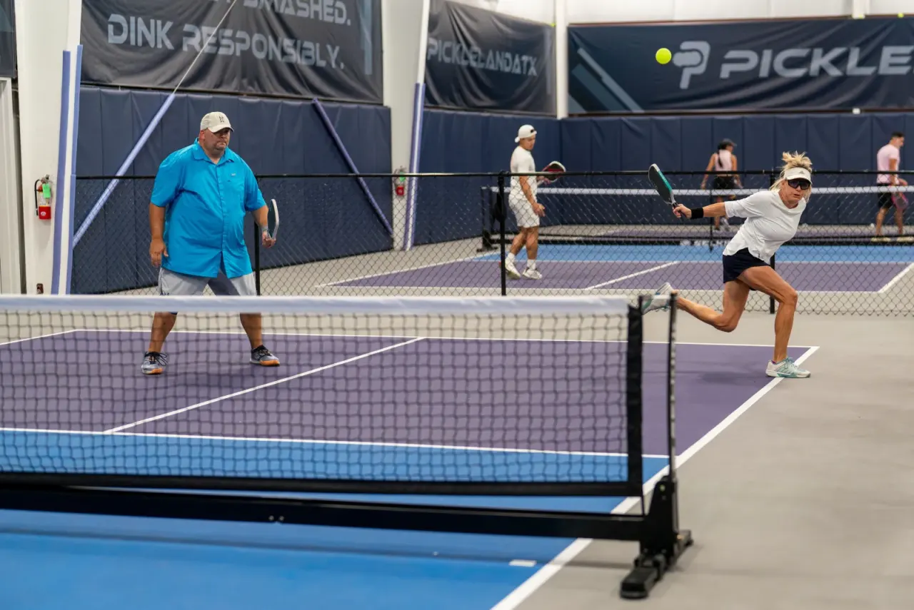 Wide view of a full indoor pickleball court at Pickleland