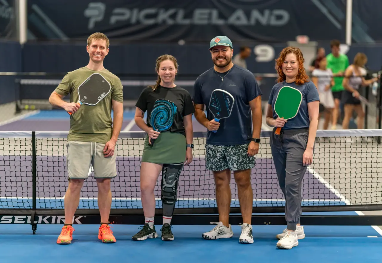 Group photo of adults at the net at Pickleland
