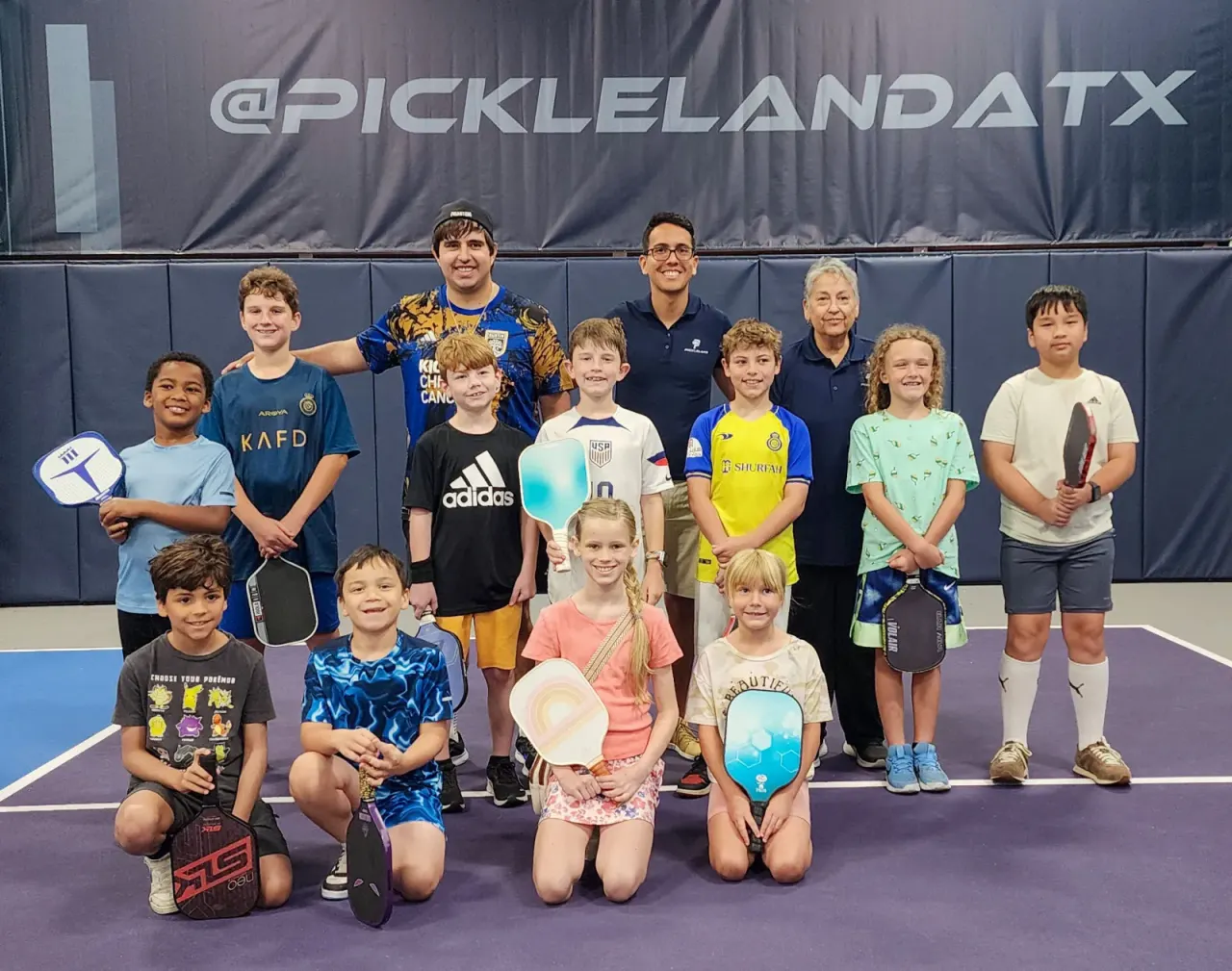 Group of kids together on court at a junior pickleball clinic