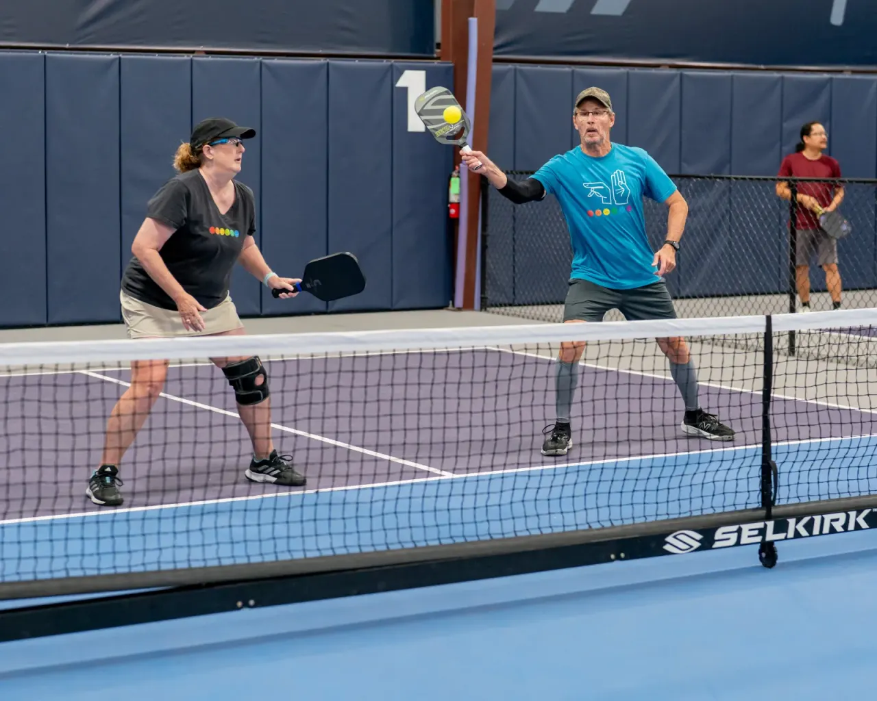 Mixed doubles action; woman wears a knee brace