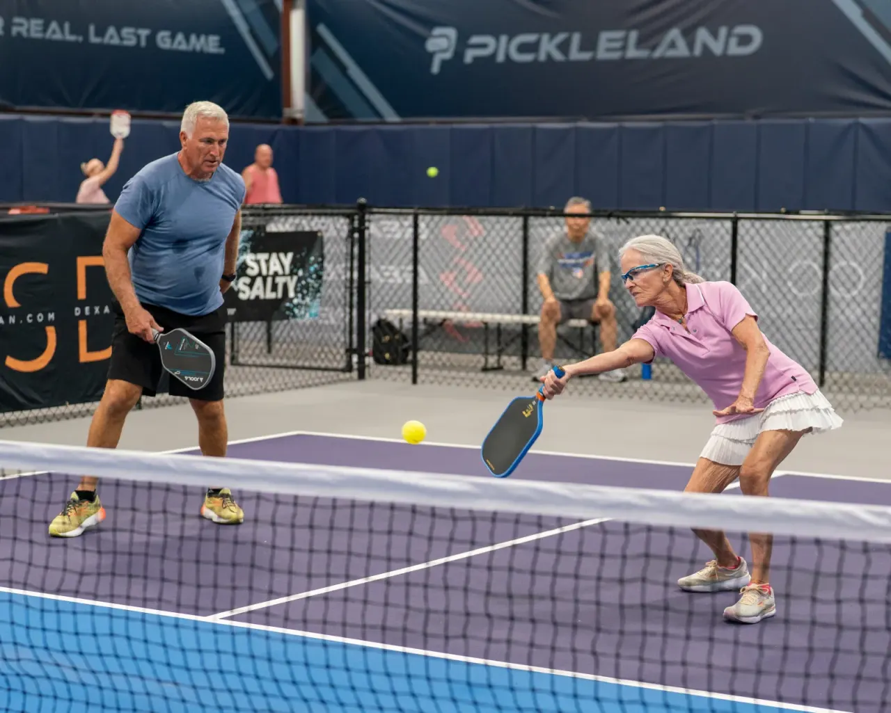 Senior woman lunging during open-play doubles to demonstrate dynamic warm-up mobility