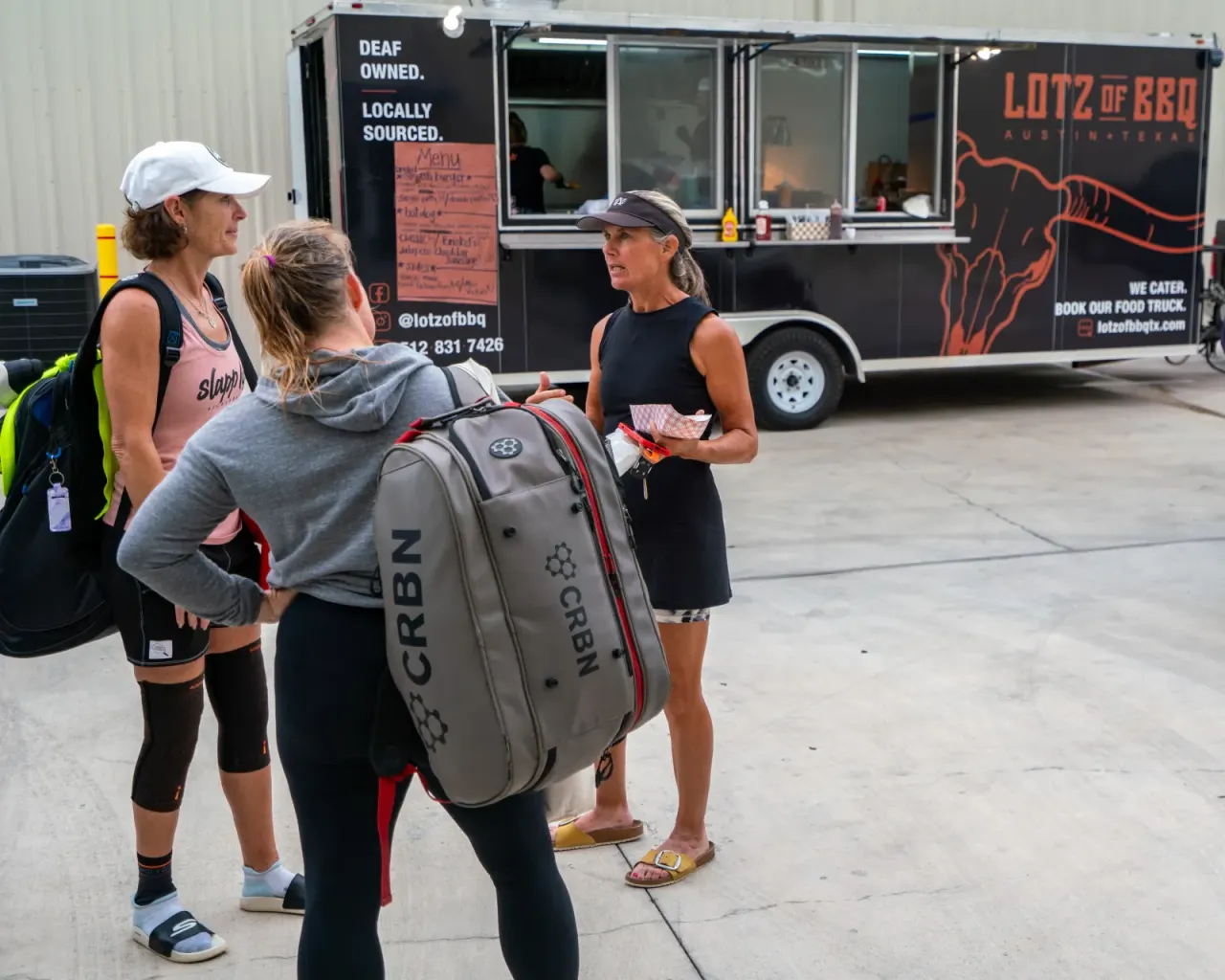 Players chat by the Lotz of BBQ food truck at an event