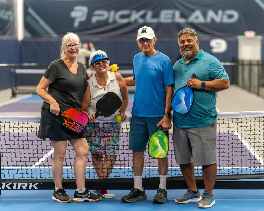 Group of senior friends together at the net with paddles