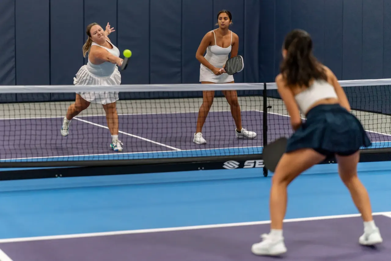 Players drilling a doubles rally on an indoor court