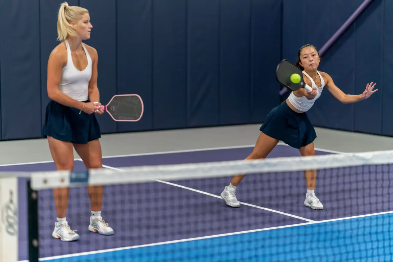 Players working on volleys during a doubles clinic on an indoor court
