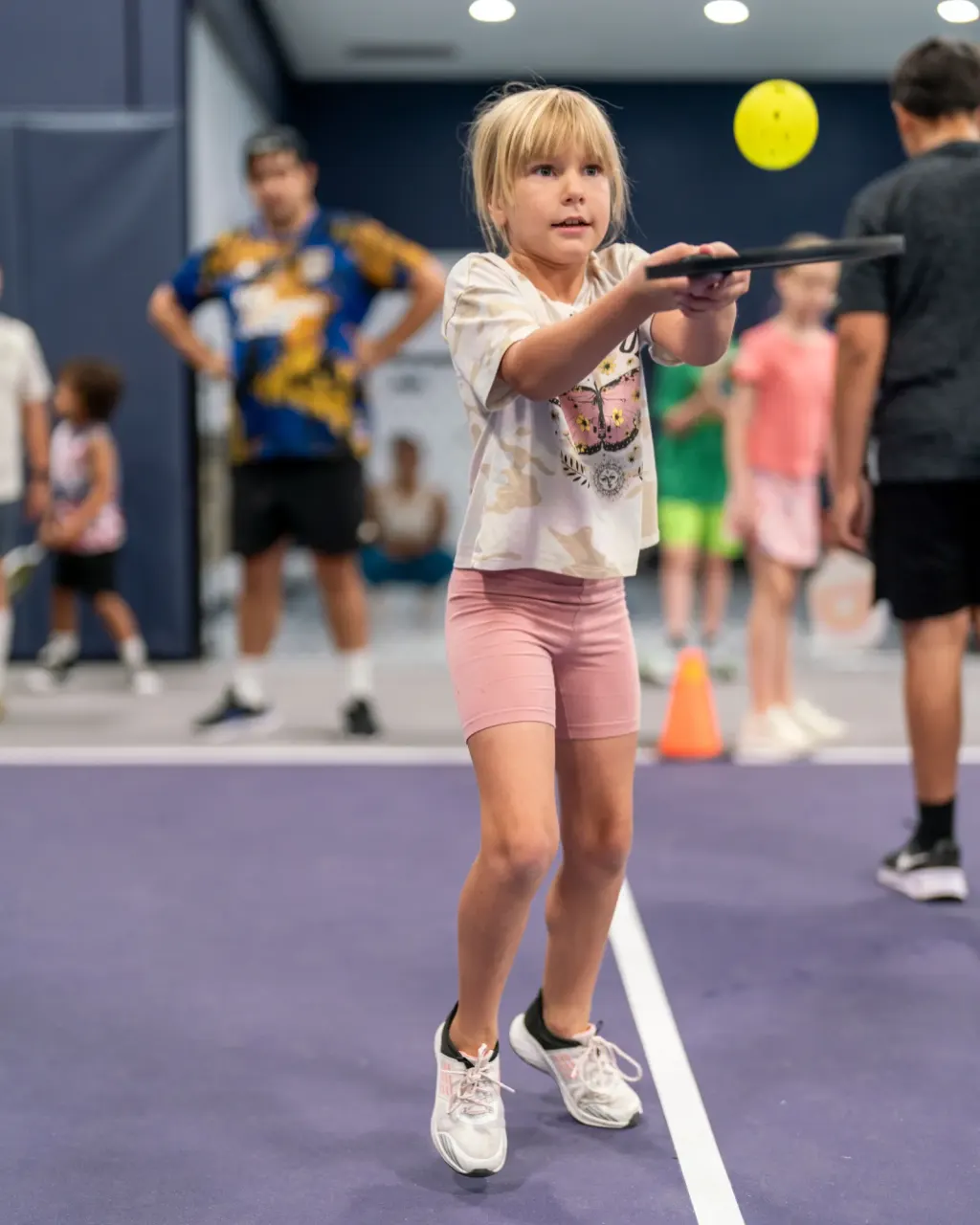 A young player hitting a forehand at a junior pickleball clinic