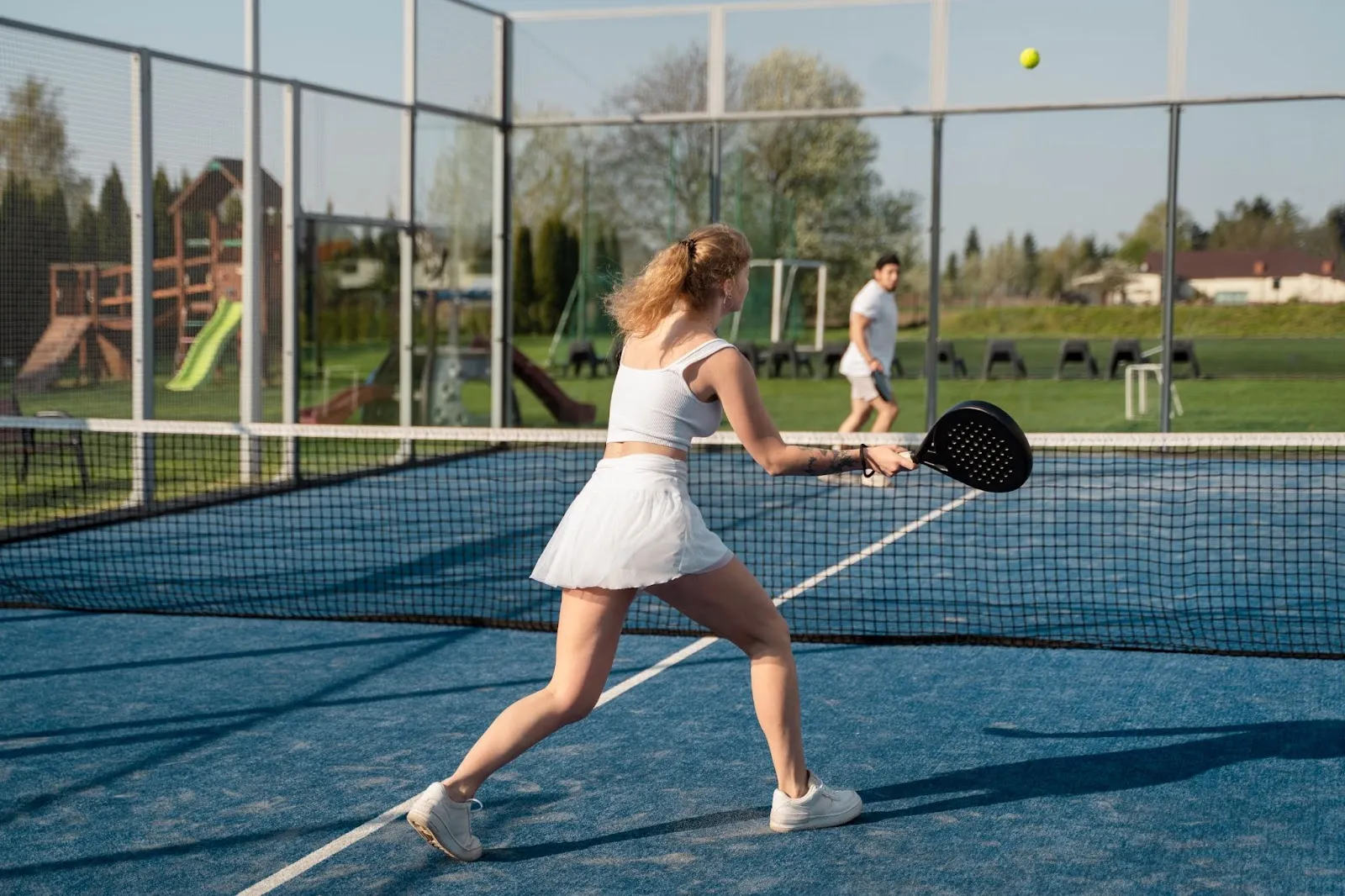 Three players rallying during a cutthroat pickleball game