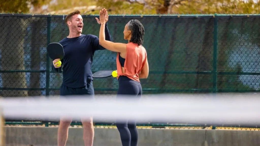 A couple sharing a laugh together during a casual pickleball date on the court